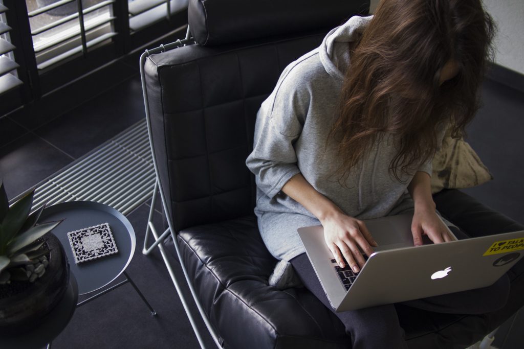 A woman works from home in a black leather desk chair 