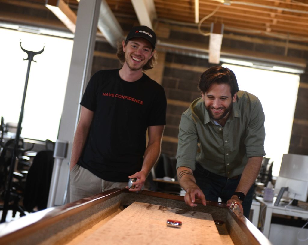 two people playing shuffleboard in the office