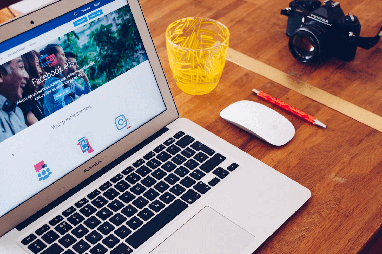 laptop, camera, glass, and mouse sitting on desk